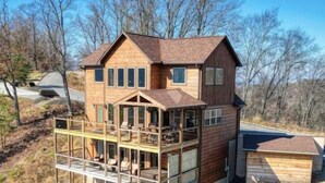A two-story wooden house with a balcony and a garage. - Thunder Bear Ridge | Mountain Views & Hot Tub (Sevierville)