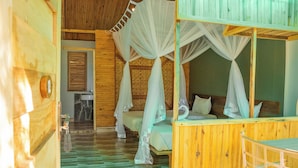 Eine Holzhütte mit einem Bett unter einer Baldachin und einem kleinen Badezimmer, außerdem ein Holzboden.