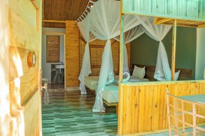 A wooden cabin with a bed under a canopy, a small bathroom, and a wooden floor. - Basecamp Resort Mweya (Mweya)