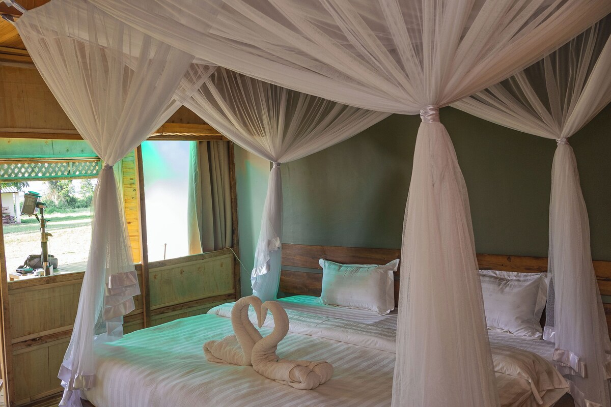 A four-poster bed with a canopy, a wooden headboard, and two swan-shaped towels.