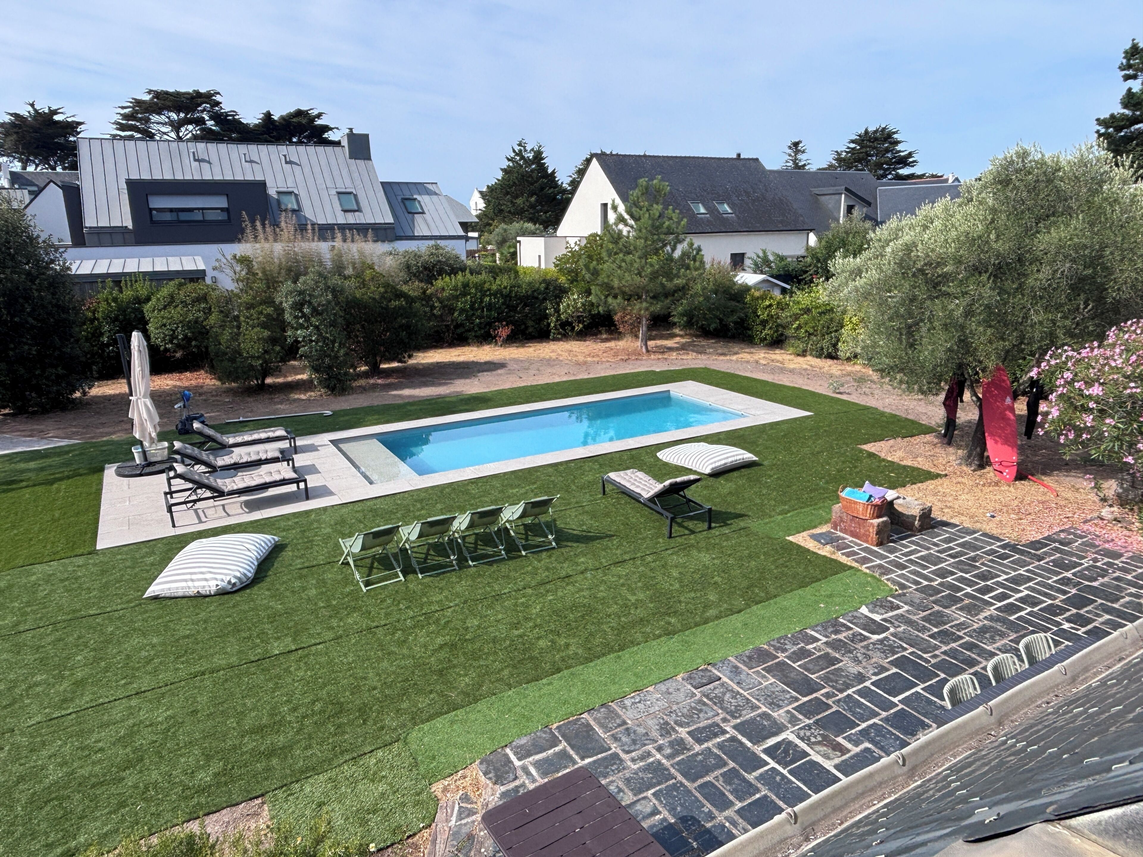 A backyard with a swimming pool, green lawn, and outdoor furniture.