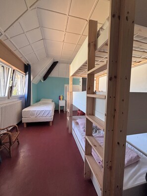 A dormitory room with bunk beds, a small table, a chair, and a radiator. - Maison 14 personnes côte sauvage Le Pouliguen / House for 14 people Le Pouliguen (Le Pouliguen)