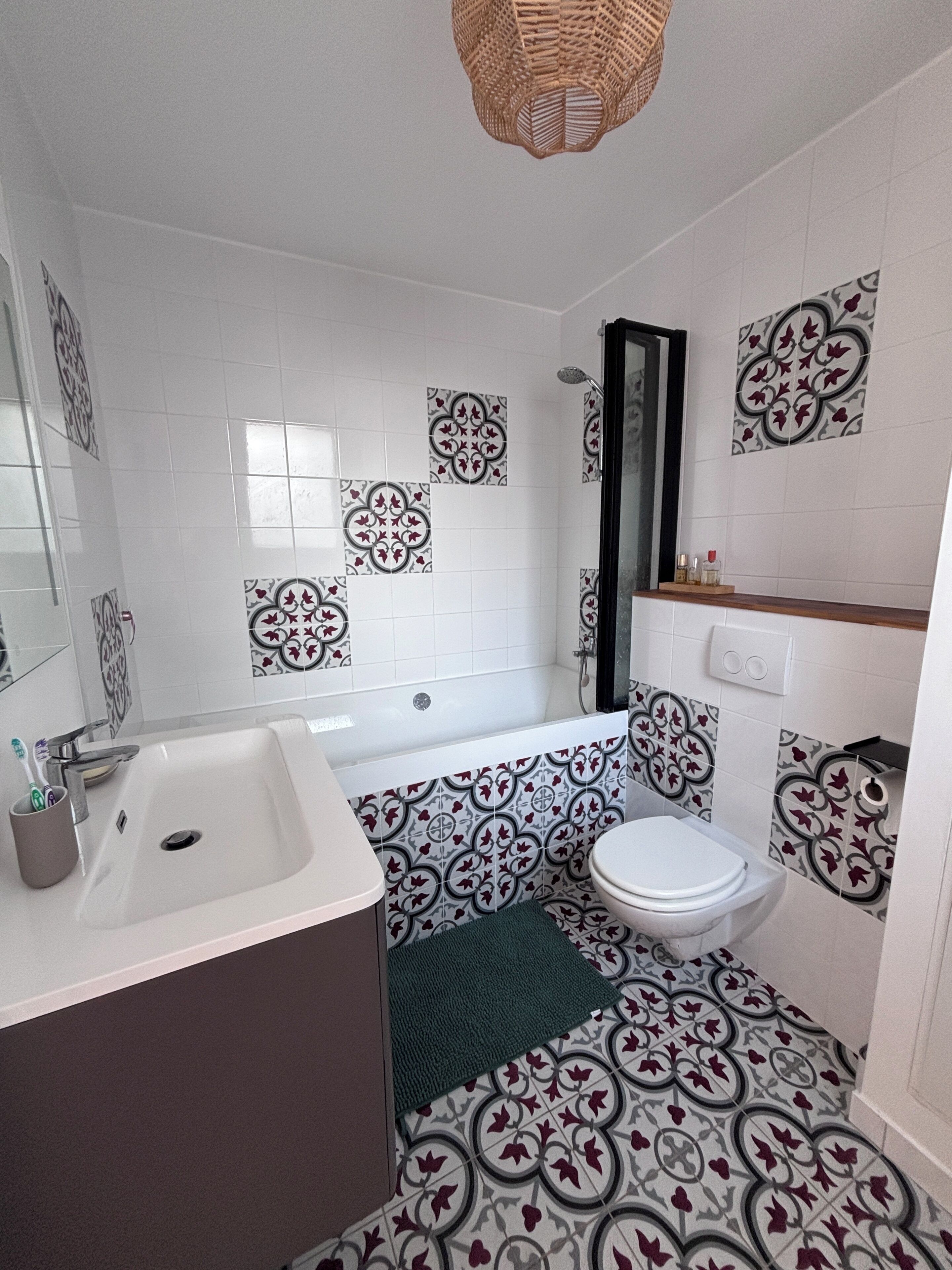 A bathroom with a bathtub, toilet, sink, and decorative tiles.