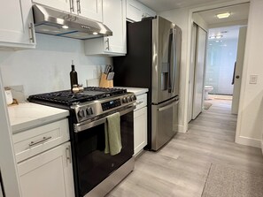 A modern kitchen with stainless steel appliances, white cabinetry, and a visible stove. - Riviera Palms - A Ryson Property (Palm Springs)