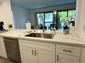 A modern kitchen with a built-in dishwasher, a stainless steel sink, and white cabinetry. - Riviera Palms - A Ryson Property (Palm Springs)