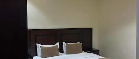 Een hotelkamer met een groot bed, een houten hoofdbord en een ronde plafondlamp.