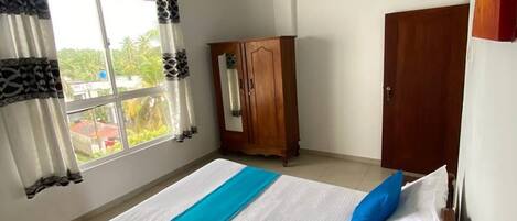 Une chambre avec un lit, une armoire et une fenêtre avec des rideaux.