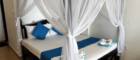 Una cama individual con dosel, un almohadón azul y un almohadón blanco.