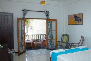A room with a bed, a chair, a table, and a painting on the wall. - PRANA Beach Hotel (Hikkaduwa)
