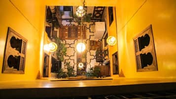 A room with a patterned wall, a hanging light fixture, and a small table with plants.