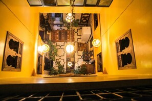 Una habitación con pared estampada, una lámpara colgante y una pequeña mesa con plantas.