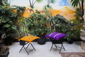 A patio with two folding chairs, a potted plant, and a mural on the wall. - Dar Berrada ziat  (Fès)