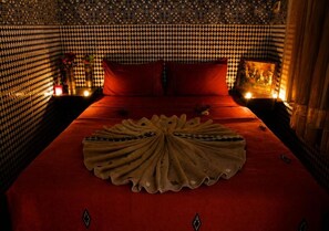 Una habitación con pared estampada, una cama con ropa de cama roja y un objeto decorativo en el centro.