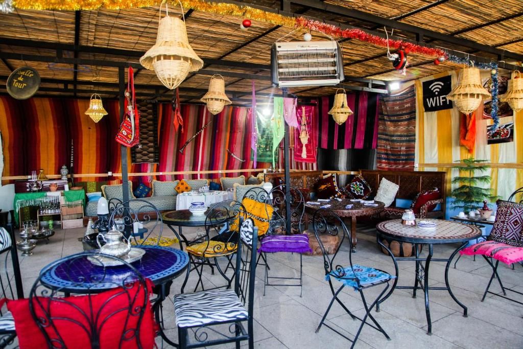 An outdoor seating area with tables and chairs, a thatched roof, and hanging decorations.
