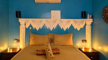 A room with a bed, a decorative headboard, bedside lamps, and a wall-mounted air conditioner.