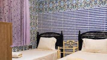 A room with two beds, a wooden wardrobe, and a window with curtains.
