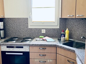 A kitchen with a built-in stove, a sink, and a window above the countertop.
