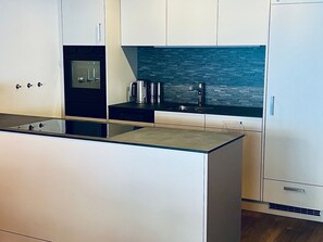 A modern kitchen with a central island, stainless steel appliances, and a backsplash with a stone-like texture. - Apartmenthaus Gauenpark (CharmingStay), (Flumserberg Tannenheim), by Interhome (Flumserberg Tannenheim)