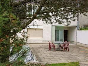 Un patio con tavolo e sedie, un muro in pietra e un edificio con una finestra e una porta.