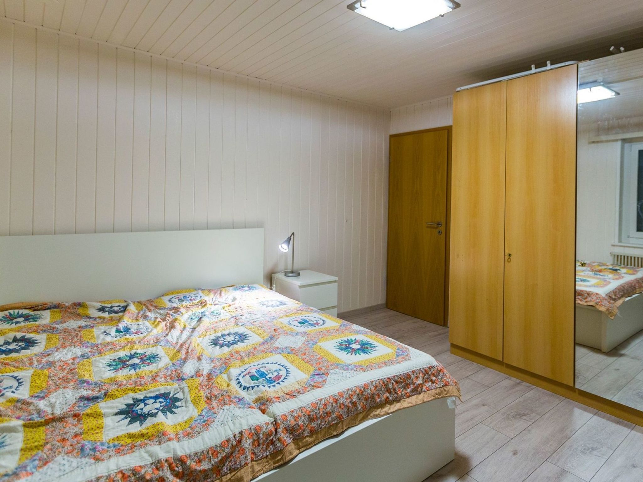 A bedroom with a bed, bedside table, and a wardrobe.