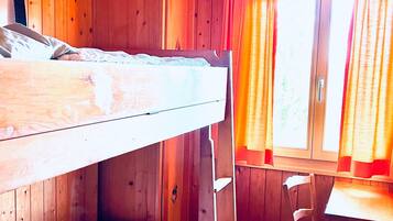 Ein Stockbett in einem Holzraum mit Fenster und Vorhängen.