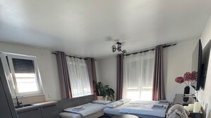 Una camera da letto compatta con un letto, un tavolino, una sedia di legno, una pianta e una finestra con tende.