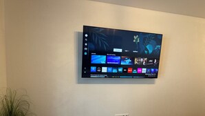 Un televisore fissato al muro mostra l'interfaccia di un servizio di streaming con diverse opzioni di contenuto.