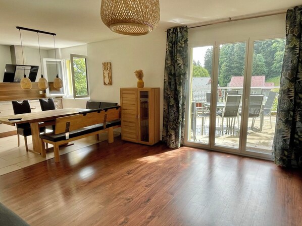 A modern kitchen with a dining area, wooden cabinets, and a large sliding glass door leading to an outdoor patio. - Haus Heimetli, (CharmingStay), (Flumserberg Tannenboden), by Interhome (Flumserberg Tannenheim)