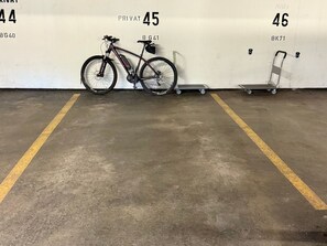 A parking area with numbered spaces, a bicycle, and a small cart. - Apartmenthaus Gauenpark (CharmingStay), (Flumserberg Tannenheim), by Interhome (Flumserberg Tannenheim)