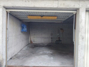 A concrete room with a ceiling fan, broom, and a blue plastic bag hanging on the wall. - Haus Panorama Reeling (CharmingStay), (Flumserberg Tannenheim), by Interhome (Flumserberg Tannenheim)