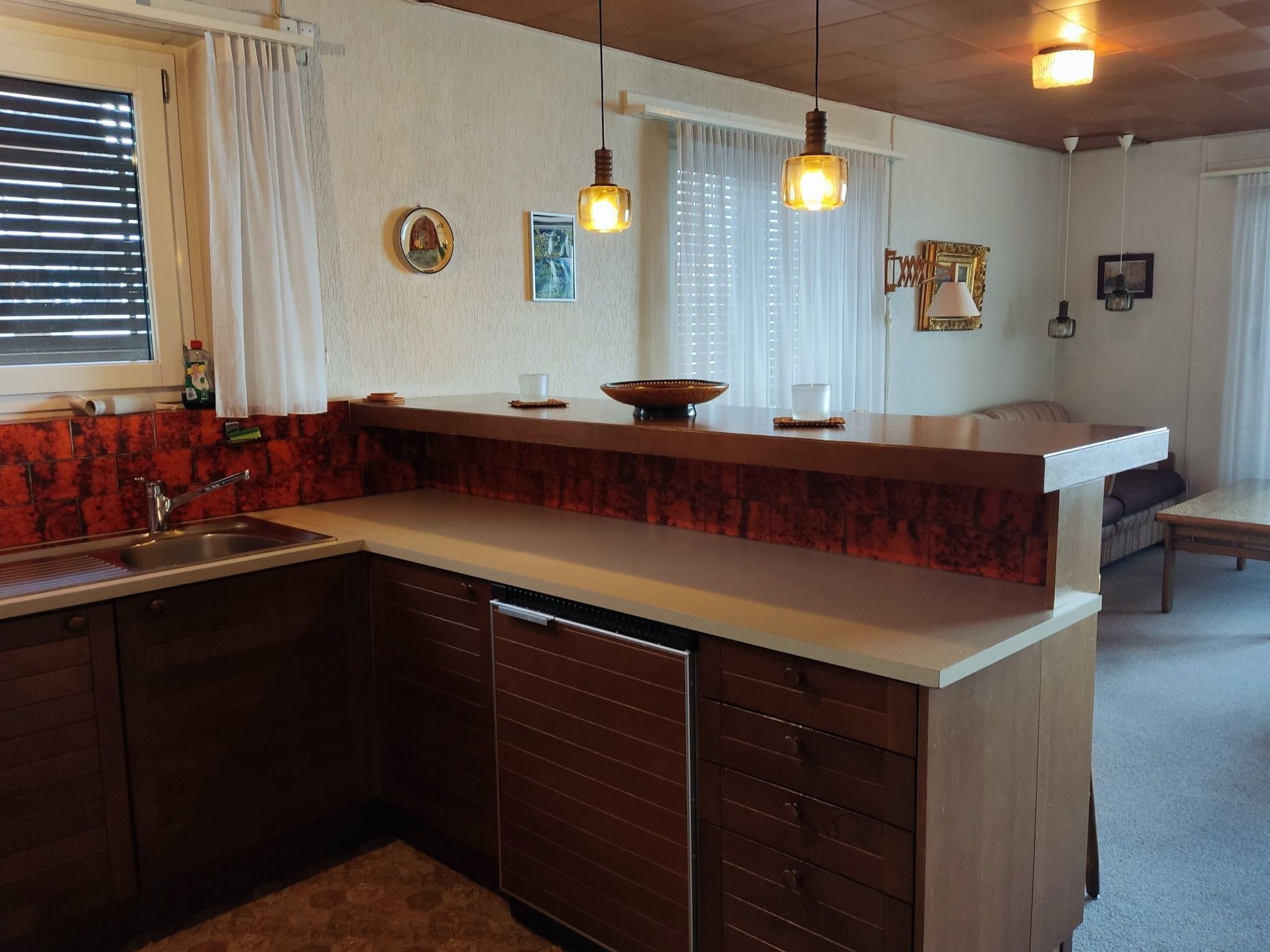 A kitchen with a built-in dishwasher, a sink, and a countertop with a bowl and a cup.