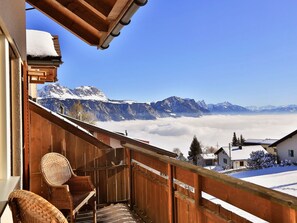 Un balcó de fusta amb vista a muntanyes cobertes de neu i un cel serè.