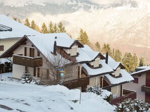 Un poble envoltat de neu amb cases de fusta tradicionals i una vista clara de les muntanyes circumdants.