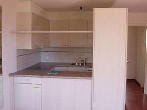 Cuina amb armaris blancs, encimera de granit i rentapelats d'acer inoxidable.