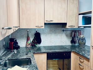 A kitchen with wooden cabinets, a dishwasher, a microwave, and a variety of kitchen utensils. - Flumser-Höckli - Casa Lilly (CharmingStay), (Flumserberg Tannenheim), by Interhome (Flumserberg Tannenheim)