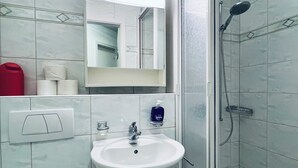A bathroom with a white sink, a mirror, a shower, and a toilet.