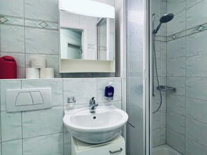 Un bagno con lavandino bianco, specchio, doccia e WC.