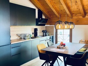 A modern kitchen with dark cabinets, a wooden ceiling, and pendant lights. - Alpenresidenz (CharmingStay), (Flumserberg Tannenbodenalp), by Interhome (Flumserberg Tannenbodenalp)
