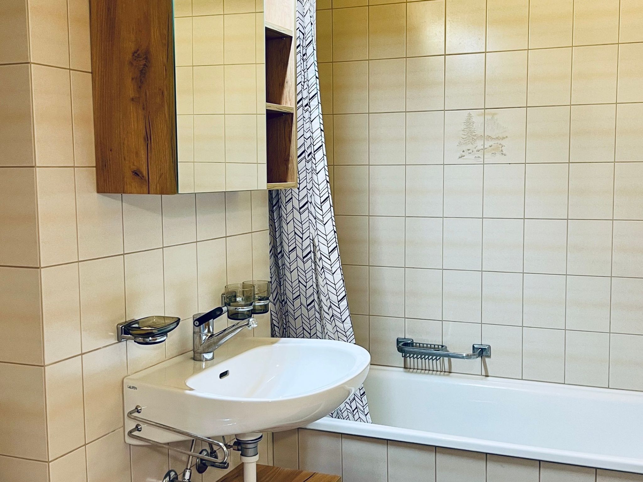 A bathroom with a white sink, a mirror, a towel rack, and a shower curtain.