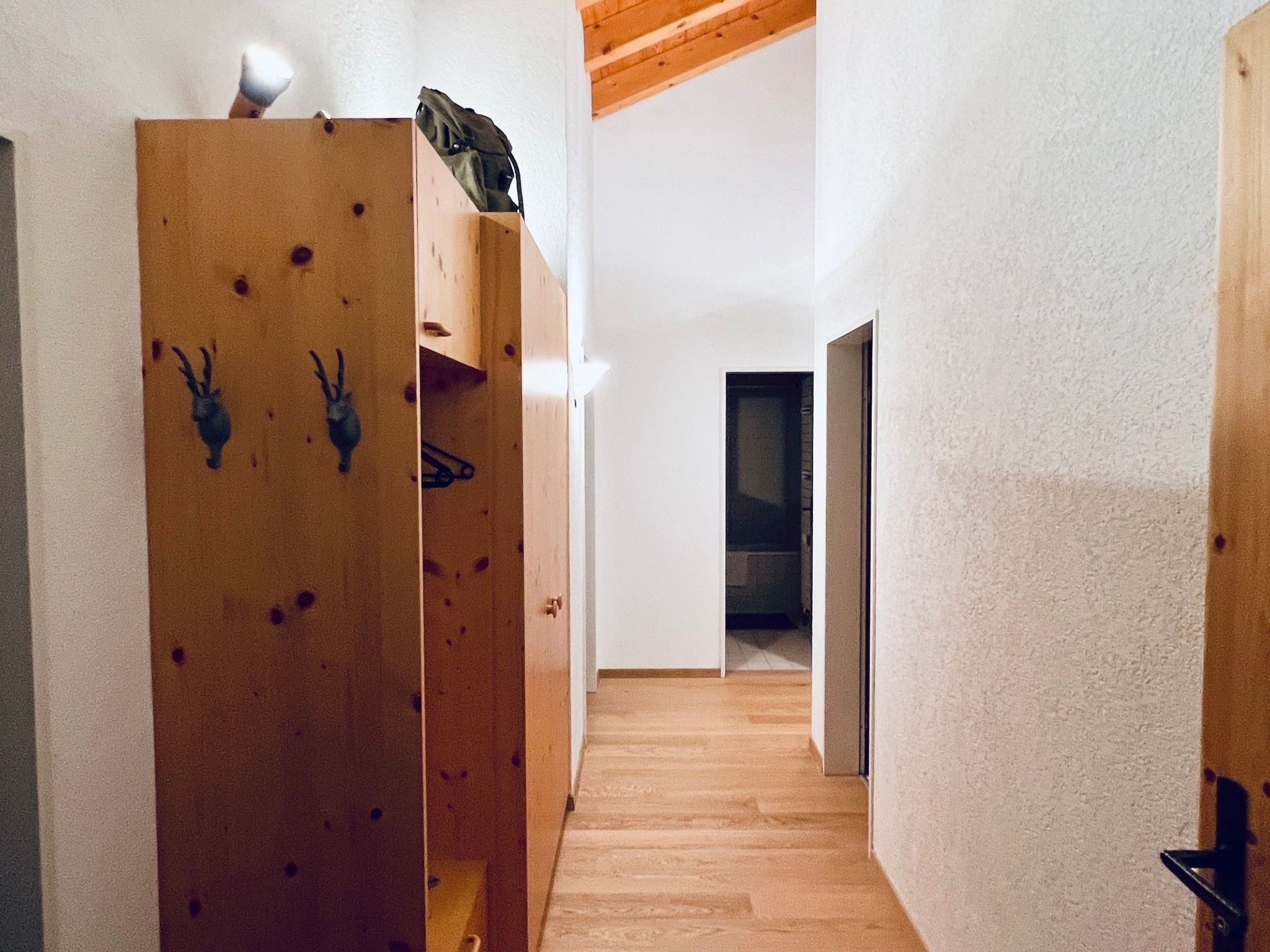Een smalle gang met houten wanden en een houten vloer die leidt naar een kamer met een donkere deur.