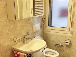A bathroom with a sink, toilet, and a window. - Haus Alpenblick A5 (CharmingStay), (Flumserberg Tannenheim), by Interhome (Flumserberg Tannenheim)