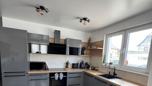 Une cuisine moderne avec des meubles de couleur grise, un plan de travail en bois et un four encastré.
