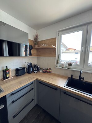 A modern kitchen with a wooden countertop, a built-in sink, and a window with a view of the outside.