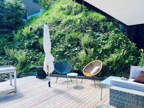 Um deck de madeira com mobiliário de exterior, incluindo uma mesa, cadeiras e um sofá.