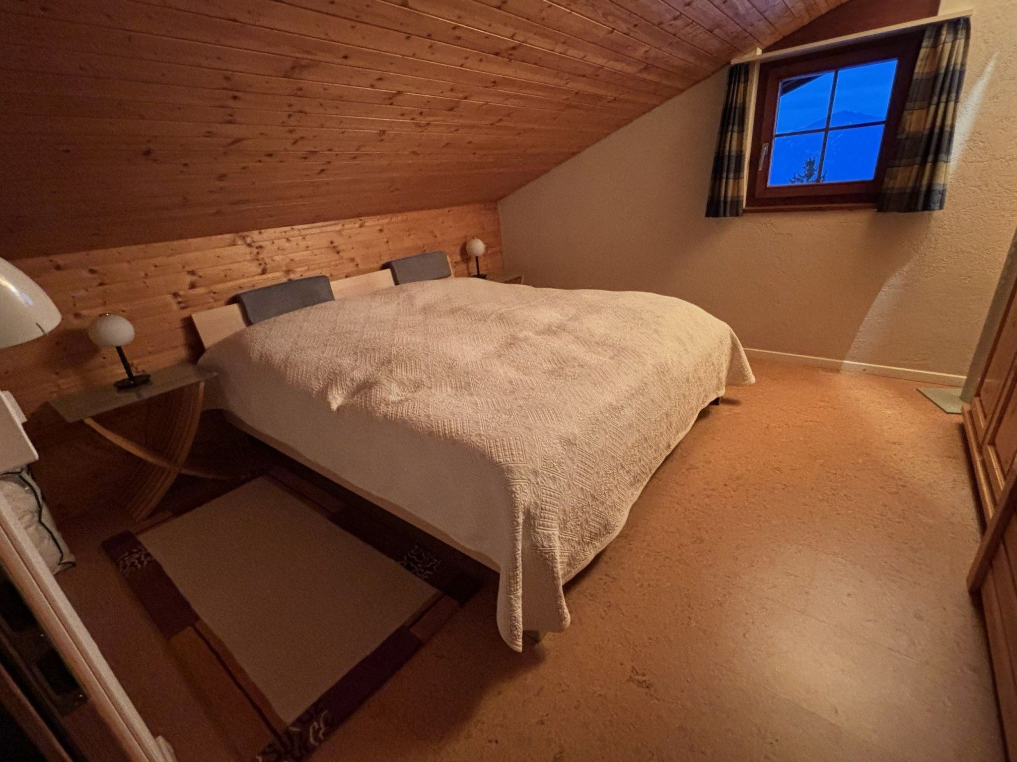 Een slaapkamer met een bed, een raam en een houten plafond.