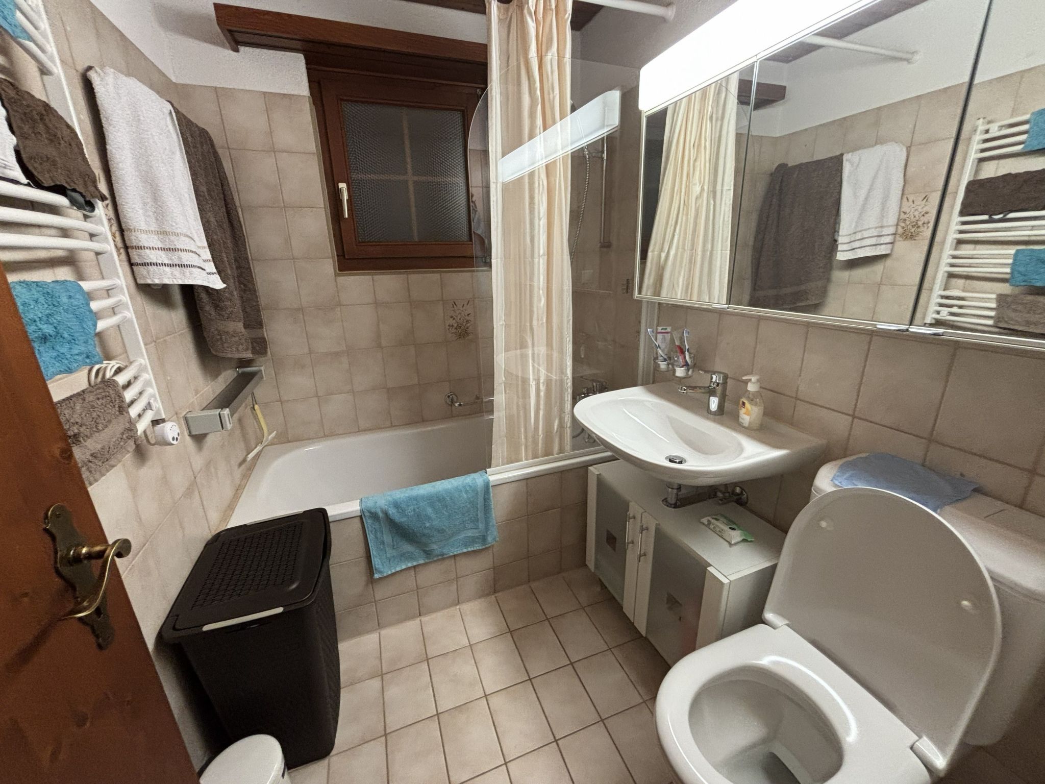 Un baño con bañera, lavamanos, inodoro y espejo.