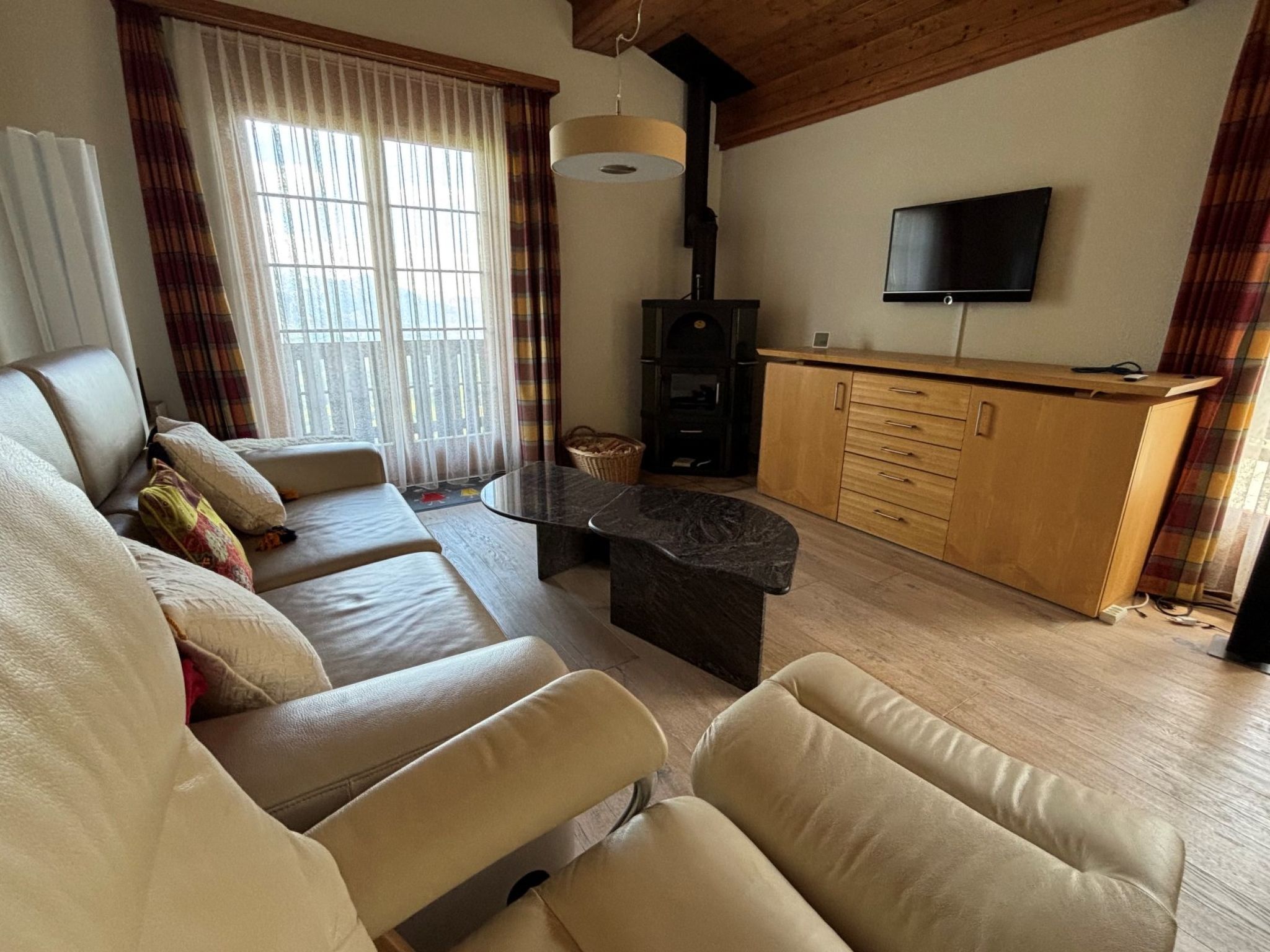A living room with a sofa, a coffee table, a fireplace, and a television mounted on the wall.