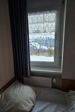 A bedroom with a window overlooking a snowy landscape. - Haus Wogesa (CharmingStay), (Flumserberg Tannenboden), by Interhome (Flumserberg Tannenheim)