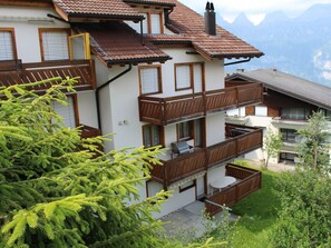 A multi-story building with balconies, a chimney, and a view of mountains.