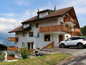 A two-story building with a ski slope, a white car parked in front, and a mountain view.